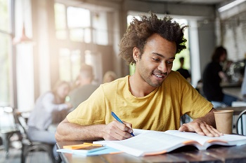 Male student writing on a book